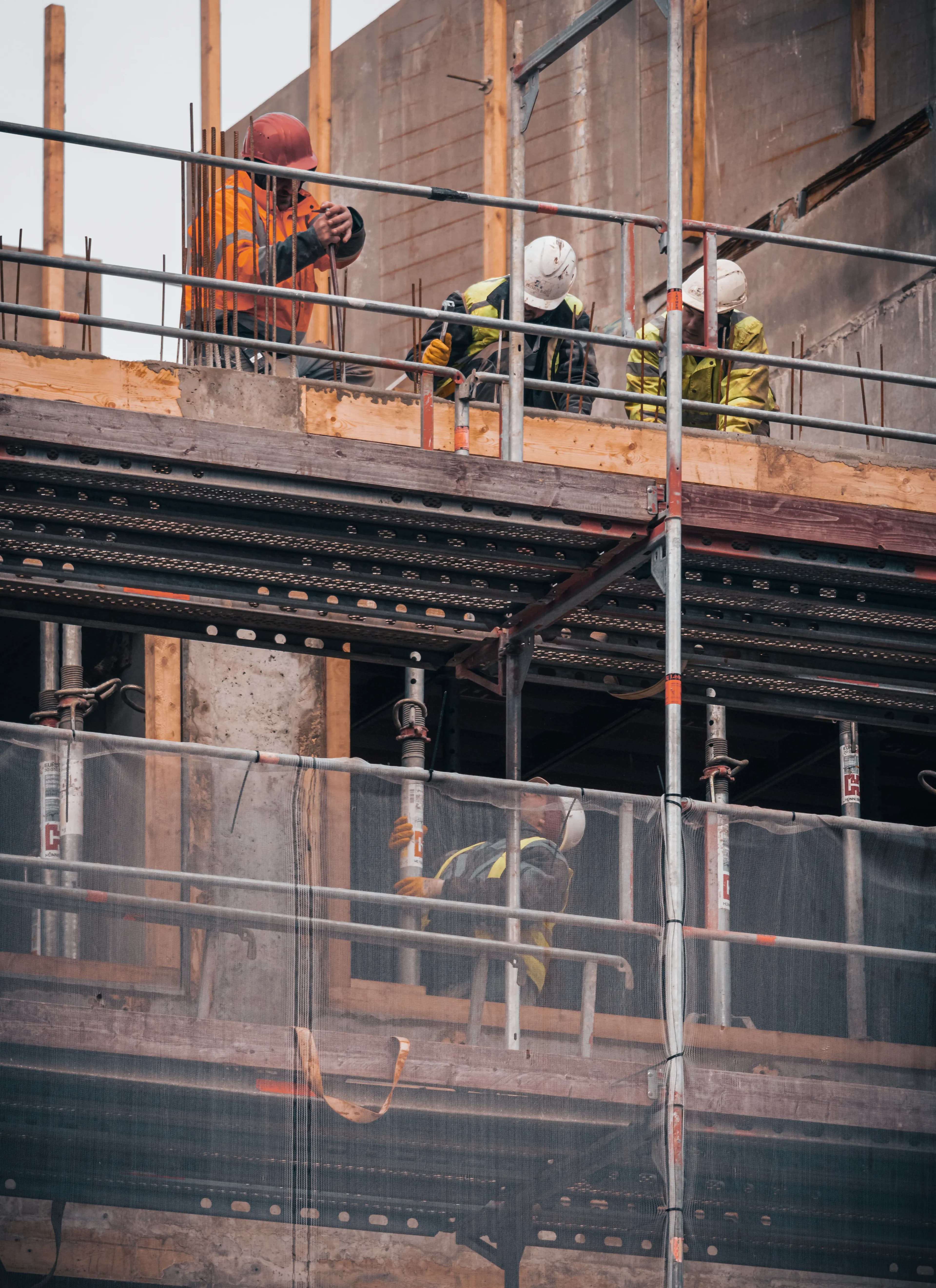 Construction workers in hard hats working on scaffolding.