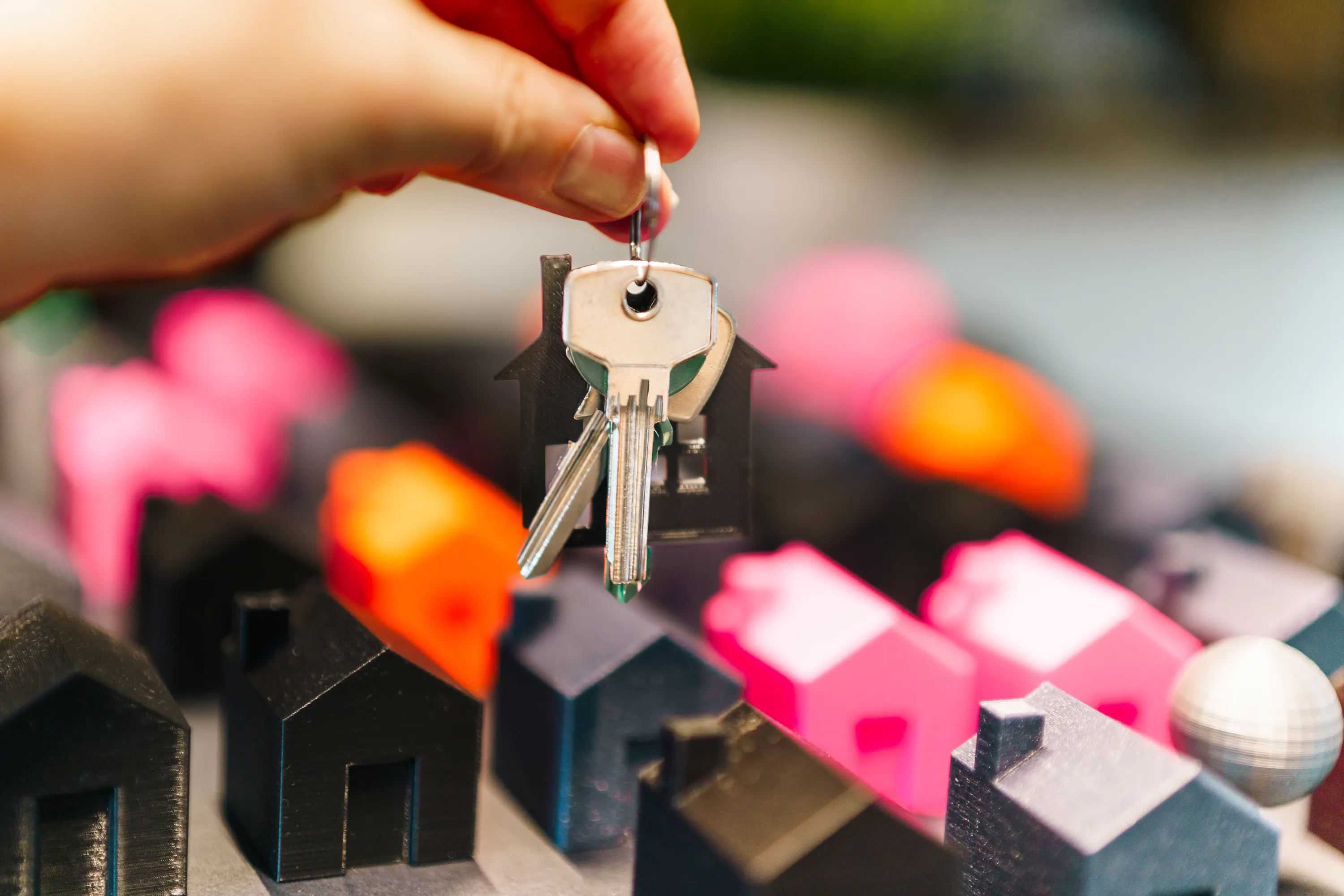 Miniature houses and keys symbolizing real estate choices.