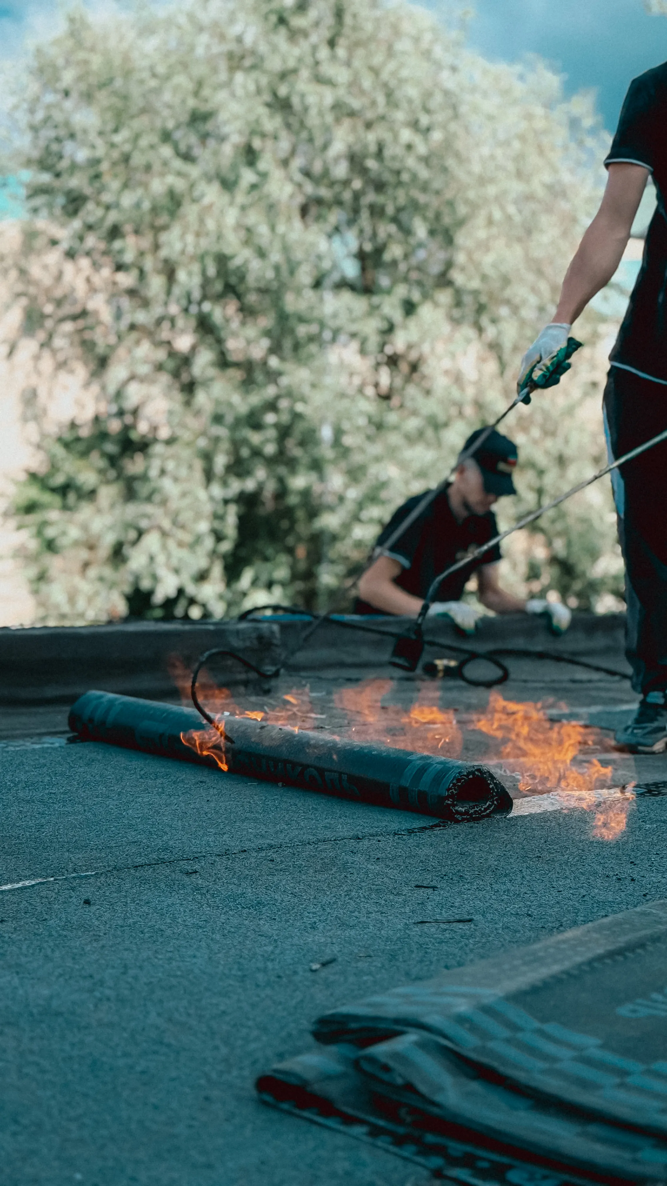 A professional roofer applying a torch-down membrane on a roof.