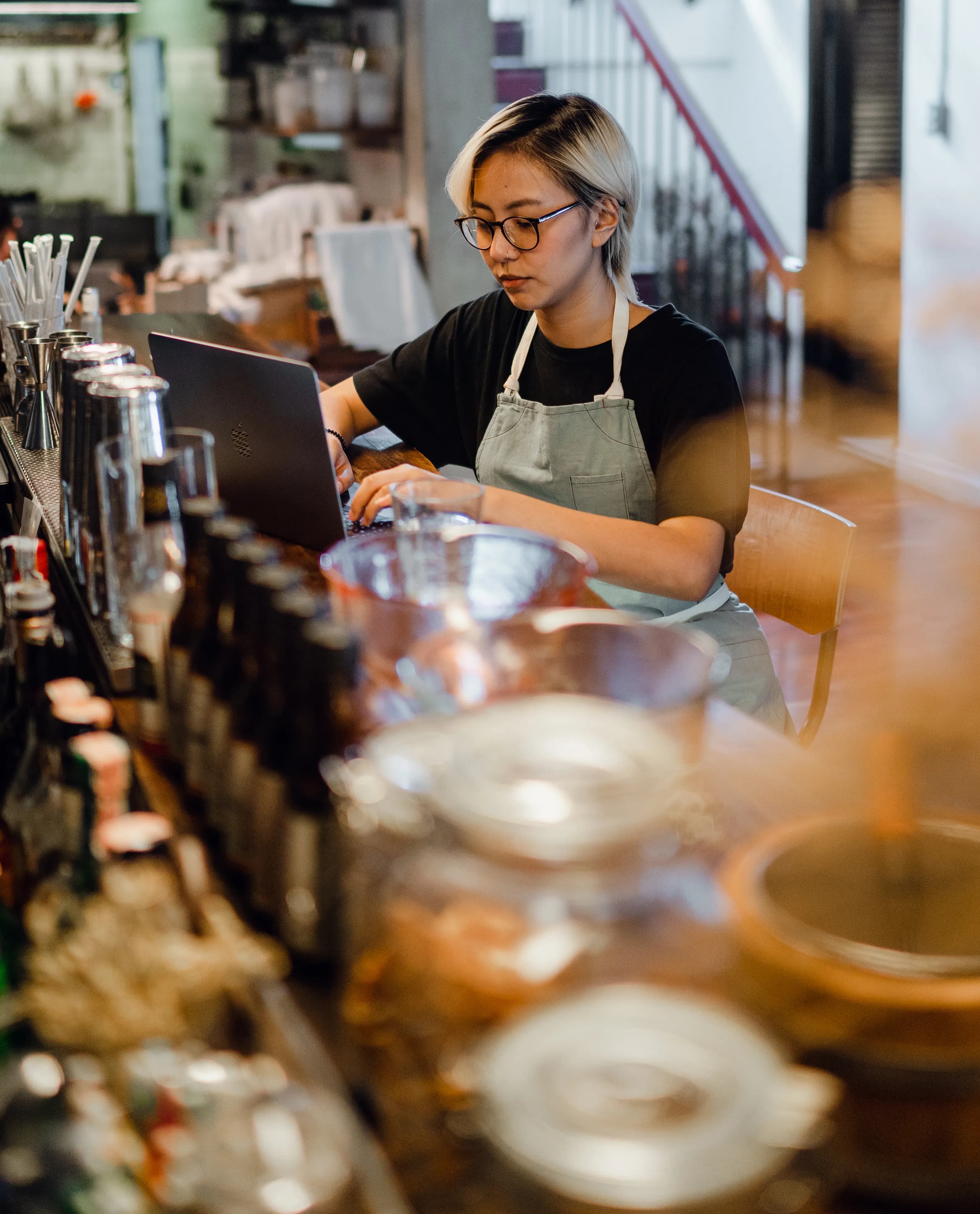 A small business owner working on a laptop in their shop, using custom business software