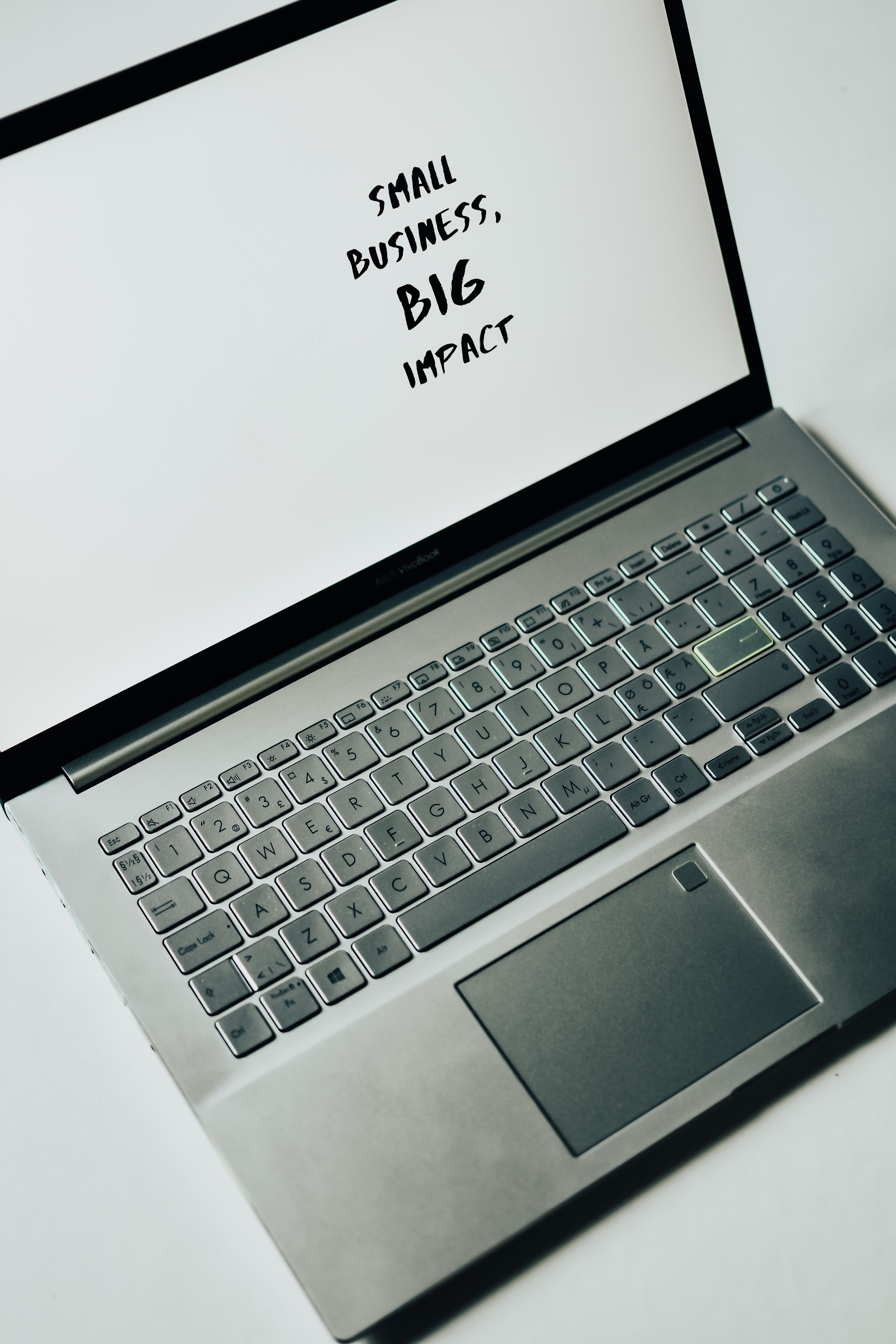 A laptop displaying the words 'small business, big impact' on its screen.